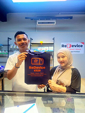 Smiling couple holding a ReDevice bag at the store counter