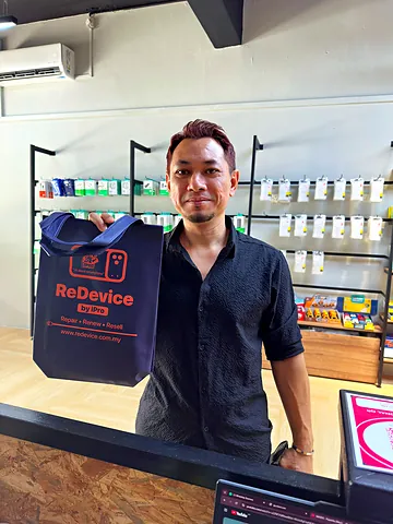 Customer in a black shirt with a ReDevice bag at the counter