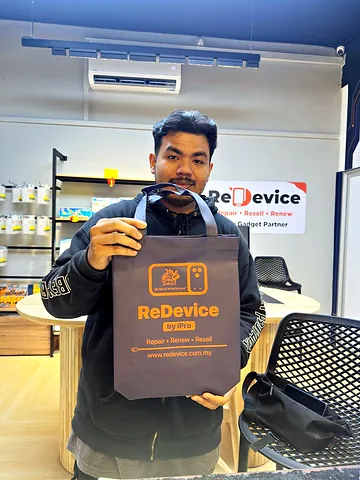 Customer in a dark jacket holding up a ReDevice bag